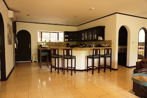 Uma cozinha ampla com ilha central, banquetas e armários escuros.