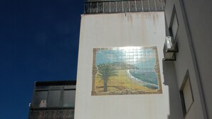 Ein Gebäude mit einem Wandbild einer Landschaft, einer schwarzen Tür und einem Balkon mit einem Metallgeländer.