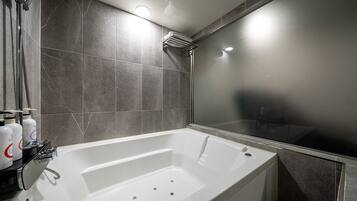 Un baño moderno con bañera, ducha y zona de ducha con paredes de vidrio.