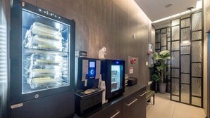 A hotel reception area with a modern design, including a digital kiosk, a refrigerator stocked with bottled water, and a decorative wall with a bear sculpture. - Anyang ILLOWA Hotel (Anyang)