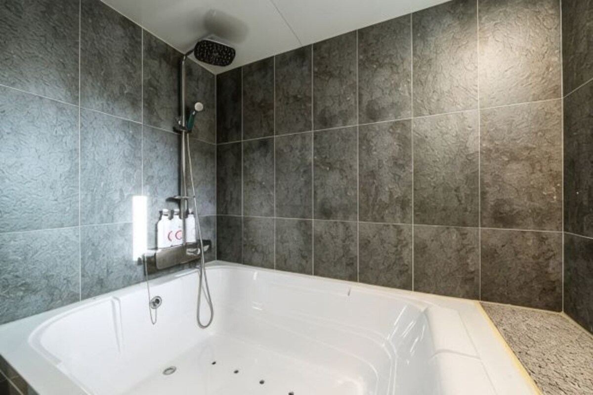 A bathroom with a bathtub, shower, and tiled walls.