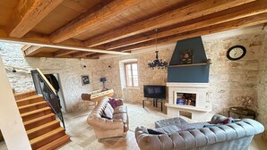 A spacious living room with a stone wall, a fireplace, a sofa, a television, and a foosball table. - Seafront Historic Villa | Private pool, kayaks and bikes (Viganj)