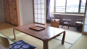 Una habitación tradicional japonesa con suelo de tatami, una mesa de madera baja y vistas a la ciudad a través de amplios ventanales.