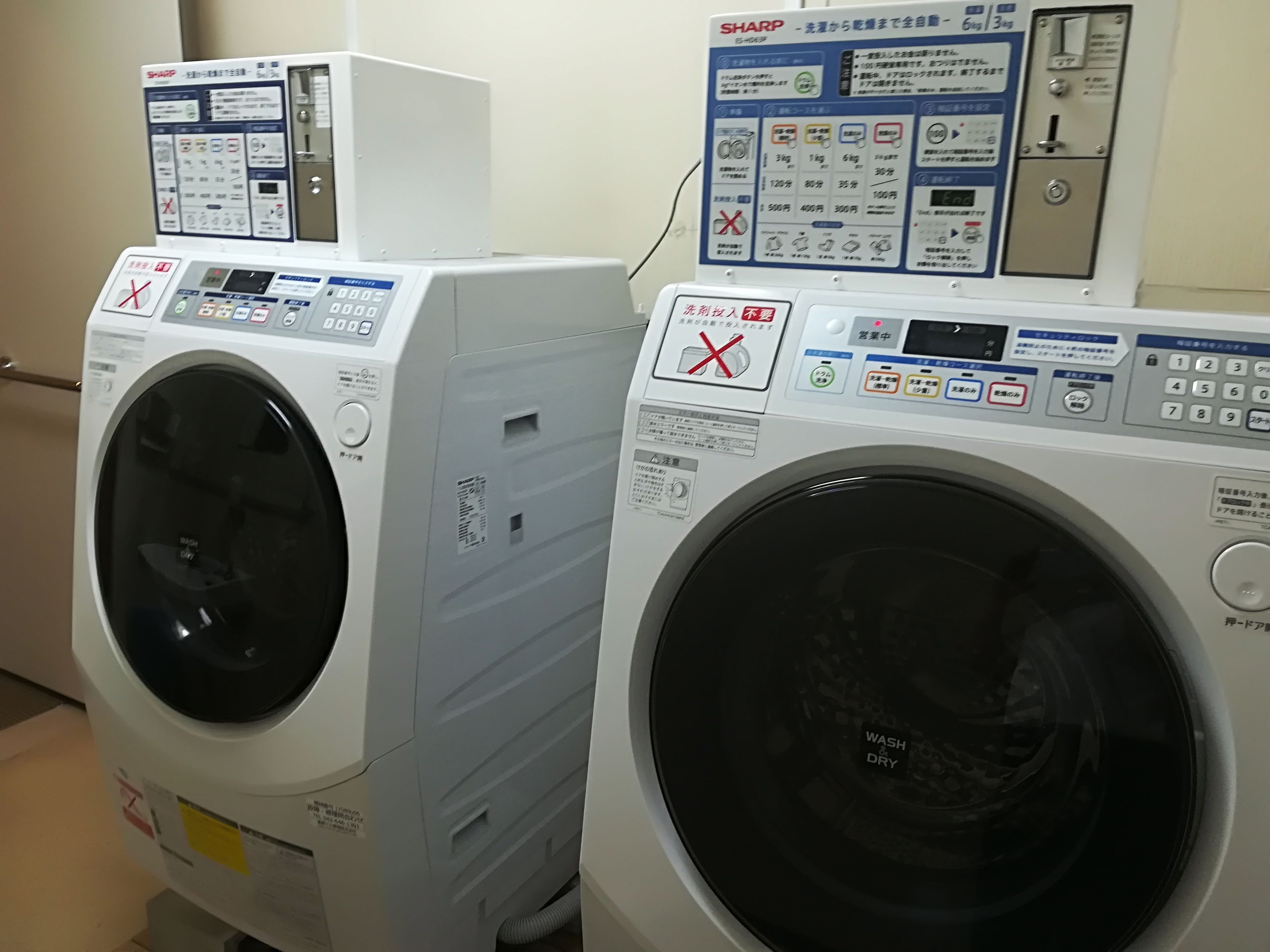 Twee voorladers wasmachines met bedieningspanelen en gebruiksaanwijzingen.