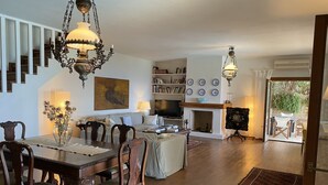 A spacious living room with a fireplace, wooden flooring, and a dining area with a table and chairs. - Breathtaking Panoramic Sea View.Private swimming pool  4,5 m X 11 m! (Kato Agios Petros)