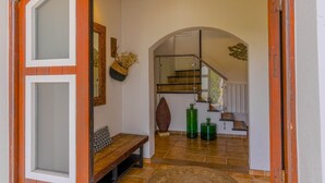 Ein modernes Interieur mit einer Holzbank, einer Glastreppe und dekorativen Vasen.