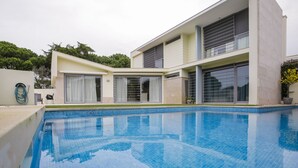 Ein modernes Haus mit Schwimmbad, großen Fenstern und einem gepflegten Rasen.