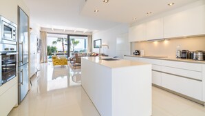 A modern kitchen with a central island, built-in appliances, and a view to the outdoors. - Designer Alcanada by Balearic Villas (Alcúdia)