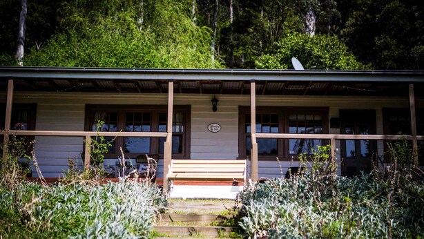 A rustic cabin with a porch, wooden steps, and a satellite dish. - Buttercuphill B&B (Warburton)