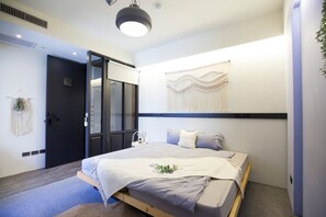 Un dormitorio moderno con cama, mesita de noche y un tapiz colgado en la pared.