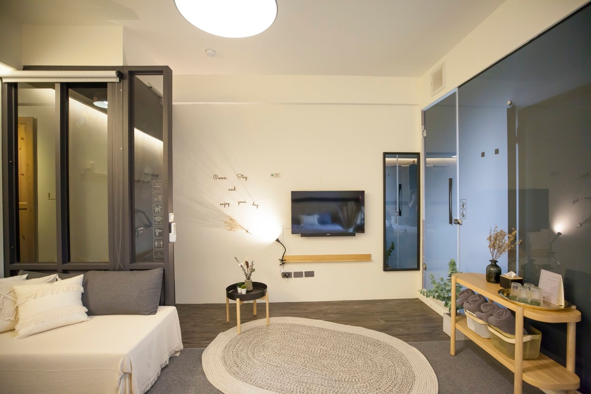 A modern bedroom with a bed, a TV, a bedside table, and a large mirror.