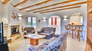 Een woonkamer met een bank, fauteuils, een salontafel, een open haard en een televisie.