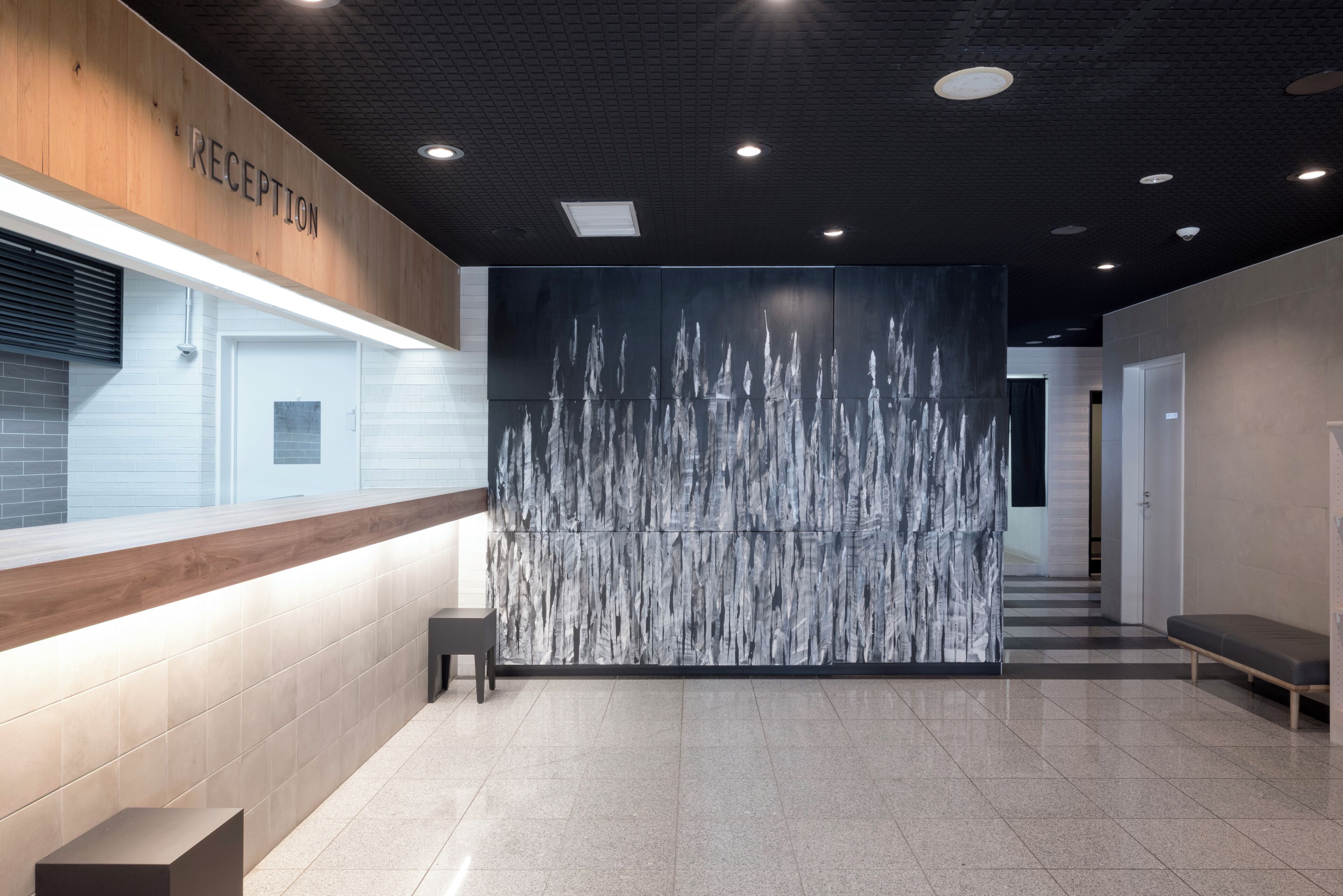 A reception area with a reception desk, a wall with a vertical water feature, and a checkered floor.