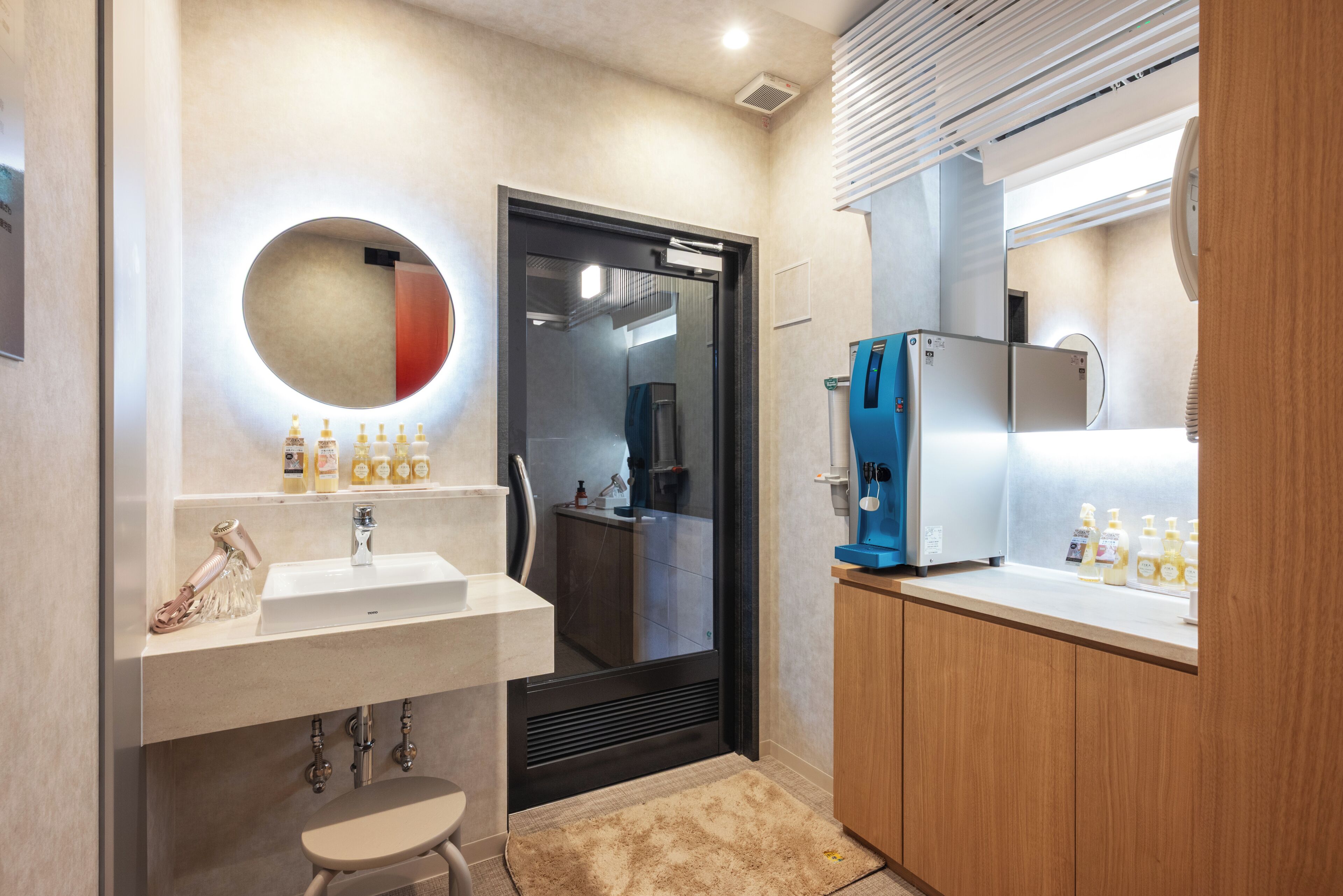 A modern bathroom with a sink, mirror, and a blue water dispenser.