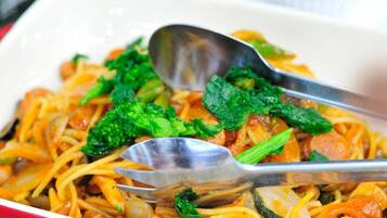A dish with noodles, vegetables, and a spoon.