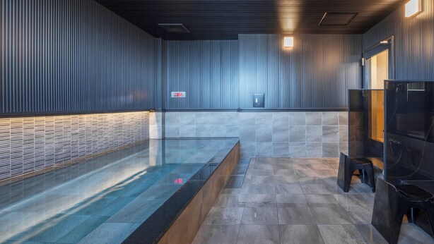 Une salle de bain moderne avec une baignoire en verre, des murs carrelés et un banc en bois.