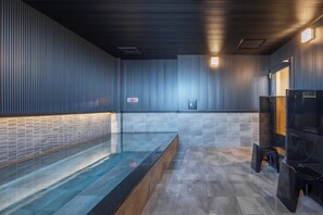 A modern bathroom with a glass bathtub, tiled walls, and a wooden bench. - HOTEL GLOBAL VIEW MORIOKA (Morioka)