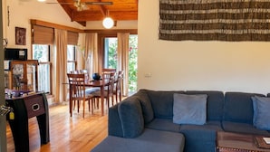 Een gezellige woonkamer met een bank, een eettafel met stoelen en een tafelvoetbaltafel.