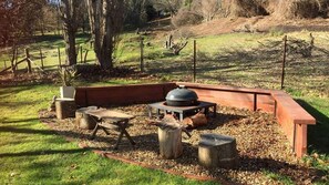 An outdoor seating area with a wooden bench, a table, and a grill.