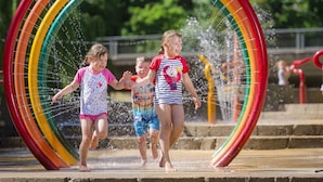 Kinderen spelen in een waterpark met een grote glijbaan in de vorm van een regenboog.