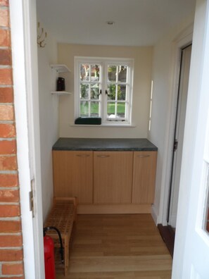 A small kitchen with wooden cabinets, a window, and a fire extinguisher.