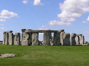 Stonehenge reser sig på en gräsklädd slätt under en klar himmel.