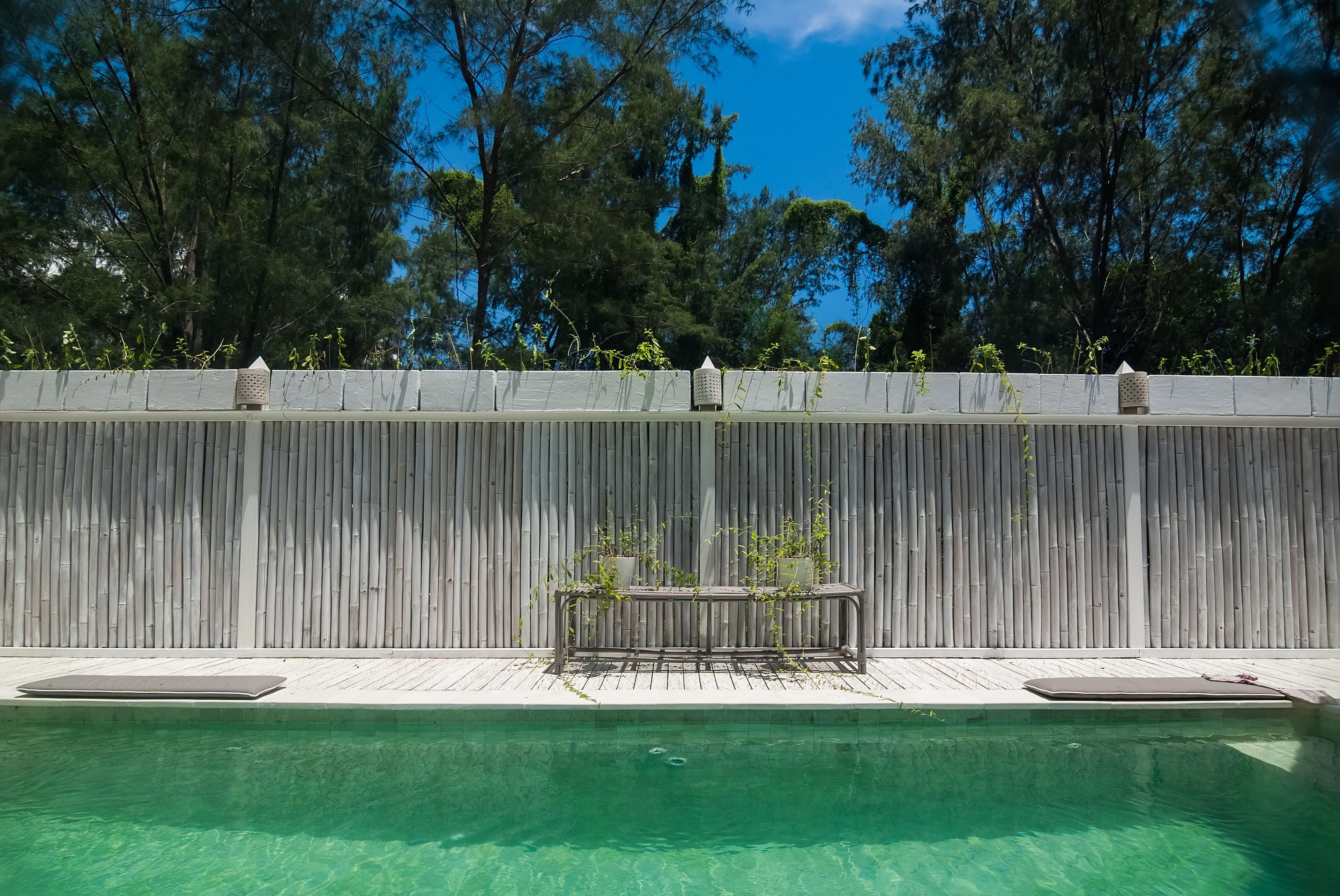 A swimming pool with a wooden deck and a metal bench.