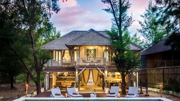 Une maison à deux étages avec une piscine, des chaises longues et un espace extérieur couvert.