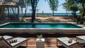Une piscine extérieure avec des chaises longues et une petite table agrémentée d’un vase de fleurs.