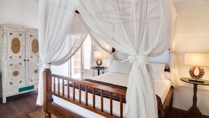 Un lit à baldaquin avec des rideaux blancs, une tête de lit en bois et une table de chevet avec une lampe.