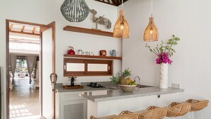 Une cuisine moderne dotée d’un îlot central, de tabourets de bar, de luminaires suspendus et d’objets décoratifs.