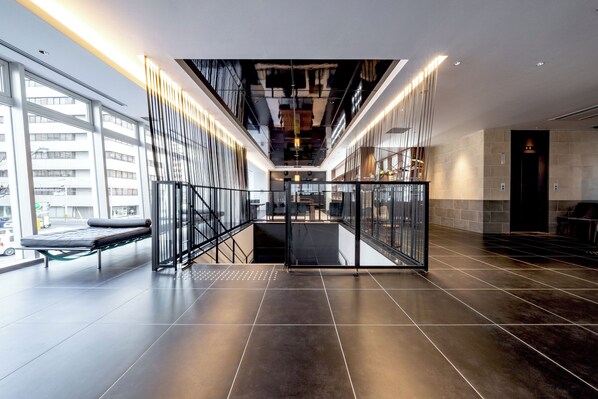 A modern interior with a glass railing, a staircase, and a view of the outside. - Hotel Vista Hiroshima (Hiroshima)
