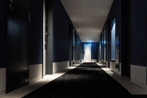 A corridor with doors on both sides, leading to a bright room at the end. - Hotel Vista Hiroshima (Hiroshima)