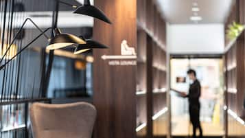 Un hall d’hôtel moderne comprenant un espace détente, un comptoir d’accueil et un fauteuil.