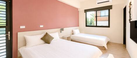Une chambre d’hôtel avec deux lits, un mur d’accent rouge, une fenêtre avec vue et un appareil de climatisation.