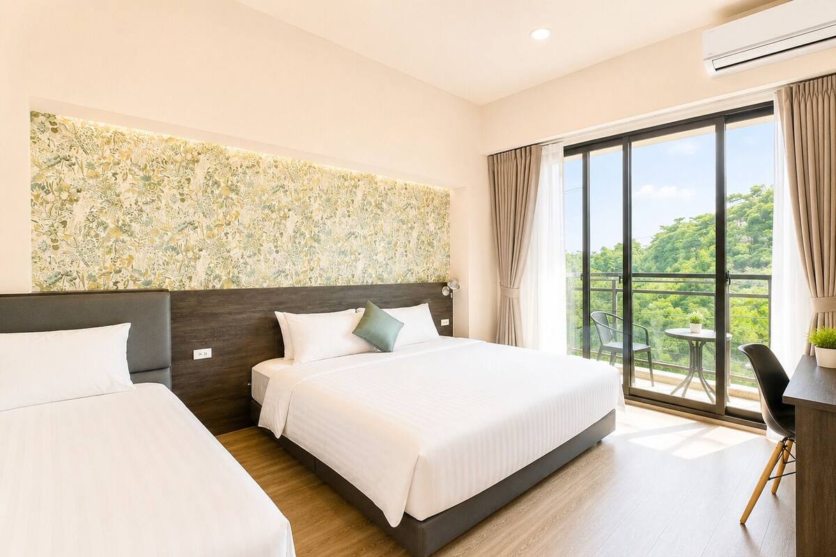 Quarto de hotel com duas camas, uma janela grande com vista e varanda com mesa e cadeiras.