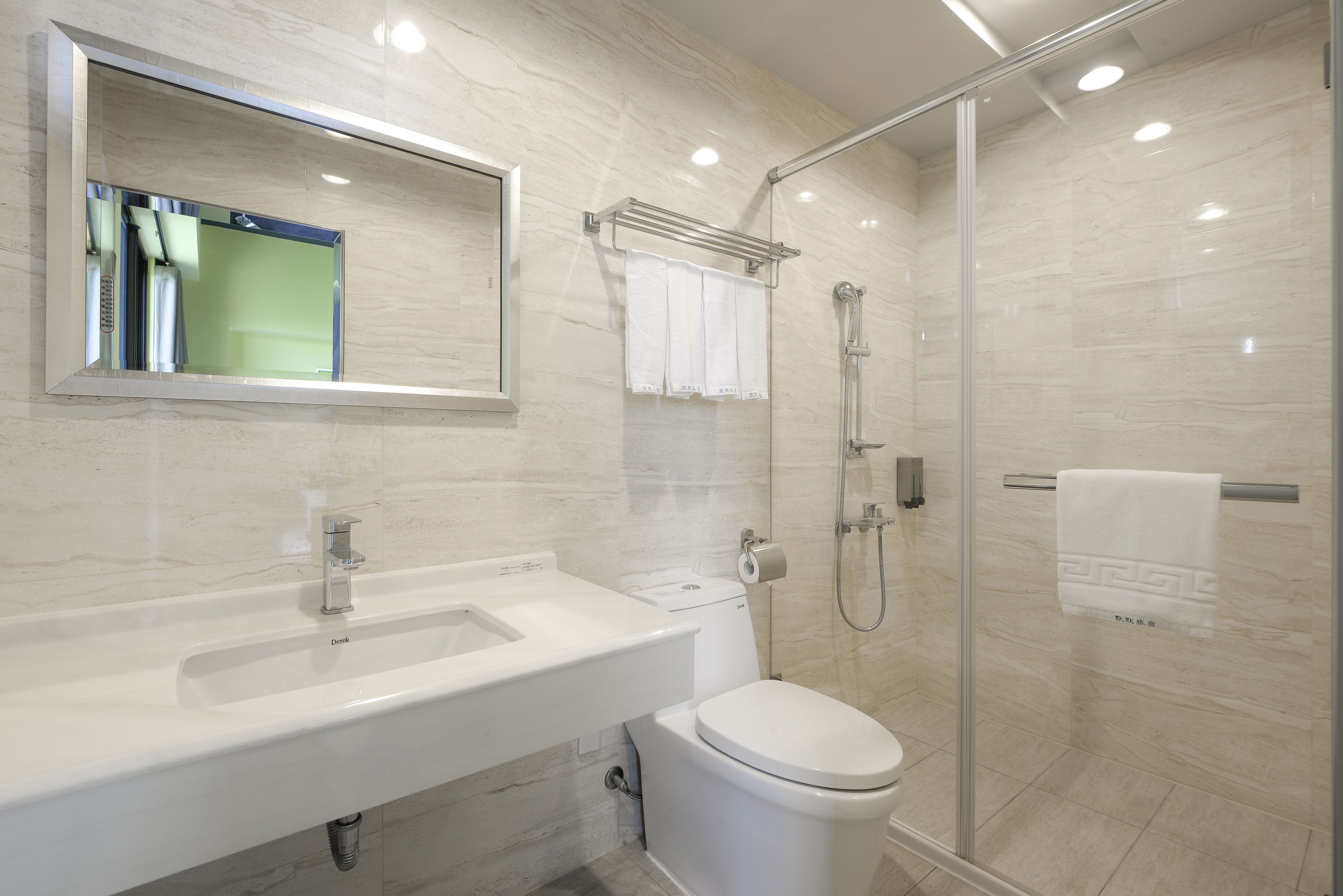 A modern bathroom with a glass shower enclosure, a white sink, and a toilet.