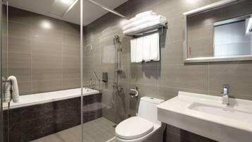 A modern bathroom with a glass-enclosed shower, a white toilet, and a sink with a mirror above it.