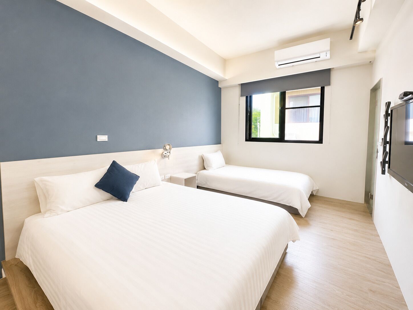 Une chambre d’hôtel avec deux lits, une fenêtre, un appareil de climatisation et un téléviseur.