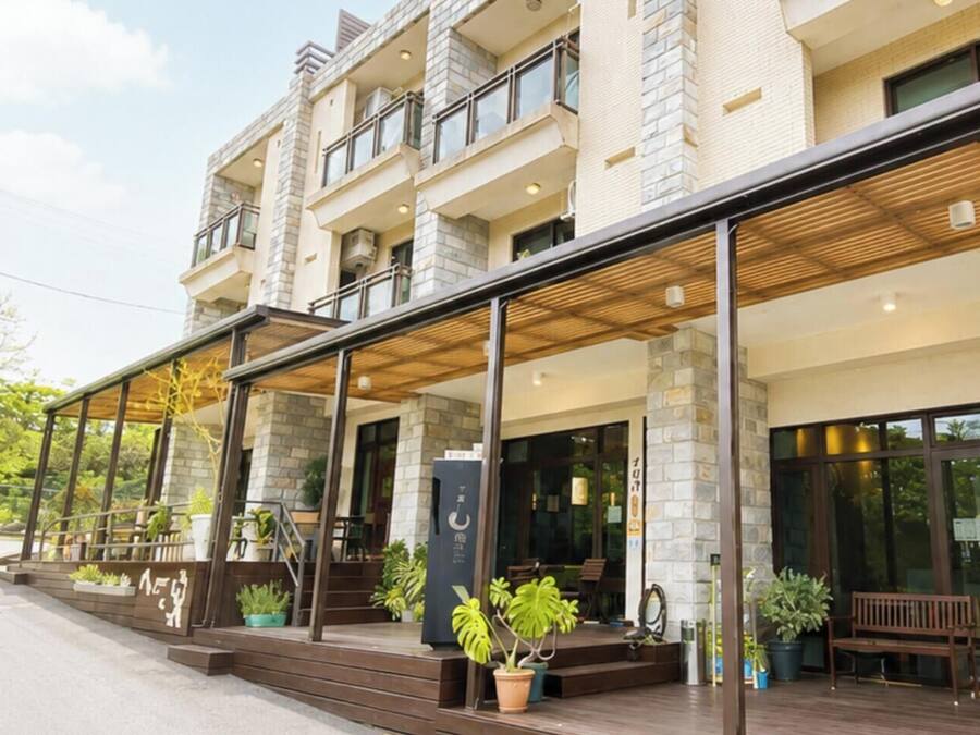 Un hotel moderno con vestíbulo cubierto, mobiliario exterior y fachada de piedra.