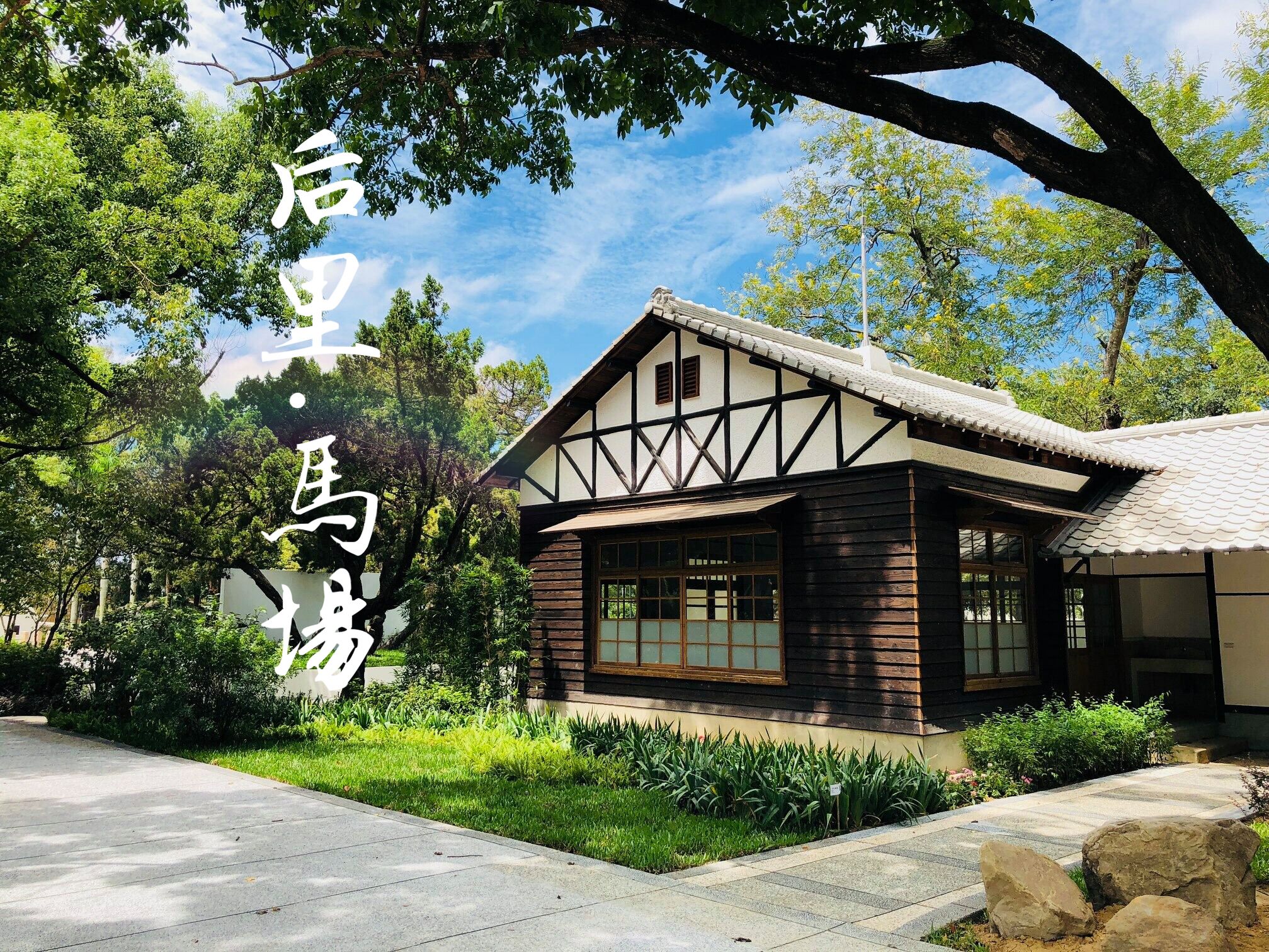 Un edificio tradicional japonés con fachada de madera y techo de tejas, rodeado de abundante vegetación.