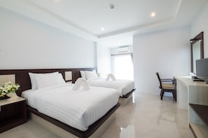 Habitación de hotel con dos camas, un escritorio, una silla y un televisor.