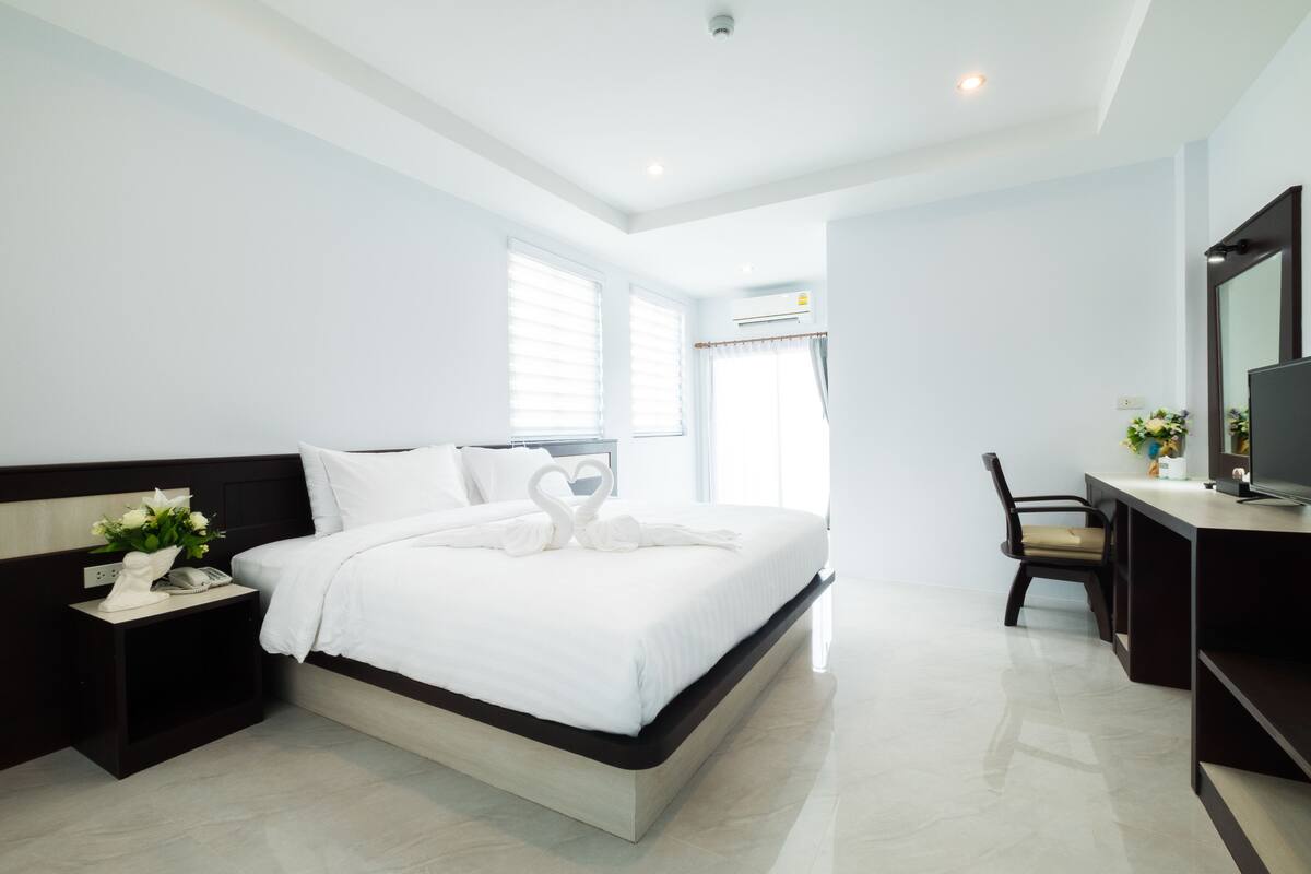 Una habitación de hotel moderna con una cama grande, un escritorio, una silla y un televisor.