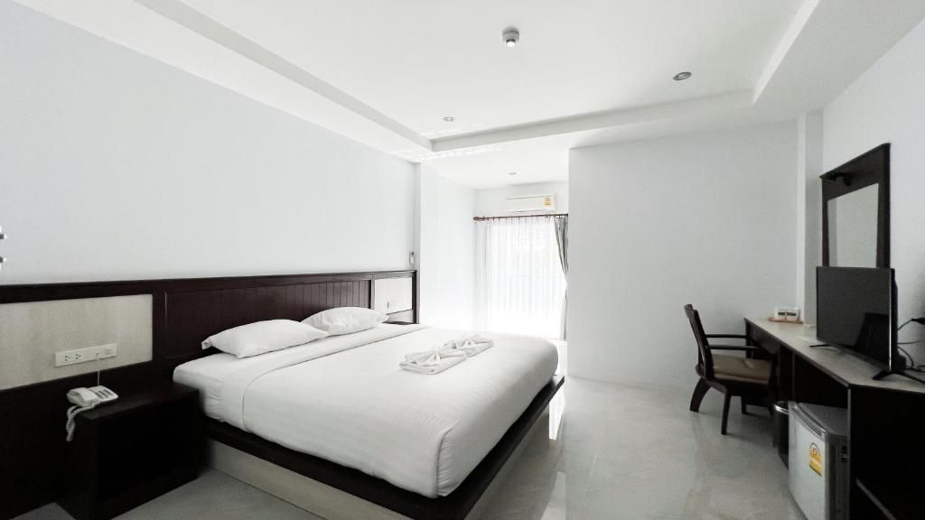 A hotel room with a bed, a desk, a chair, a mirror, and a window with curtains.