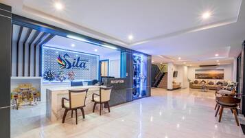 Ein Hotel-Rezeptionsbereich mit modernem Design, einem Empfangstresen und einer Sitzecke mit Stühlen.