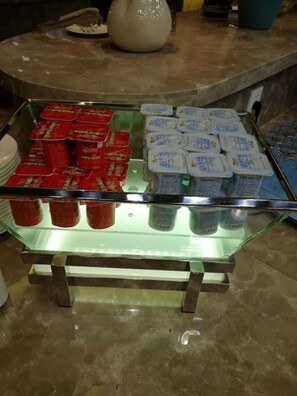 Vitrina con productos alimenticios envasados en rojo y blanco, probablemente lácteos, sobre un estante de vidrio en un entorno comercial.