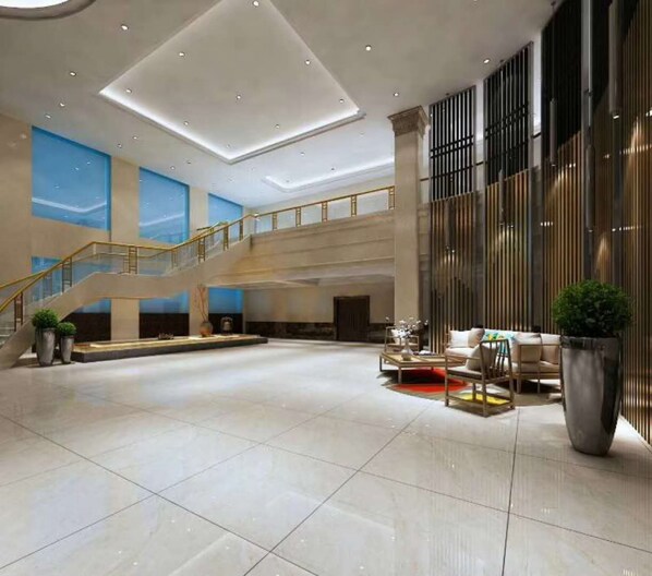 Un hall d’entrée spacieux avec un plafond haut, un escalier et un coin salon comprenant une table basse et des fauteuils.