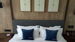 Habitación de hotel con cama, almohadas, colcha verde azulada acolchada y cisnes decorativos hechos de toallas.