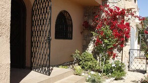A building entrance with a stone facade, a metal gate, and a staircase leading to the door.