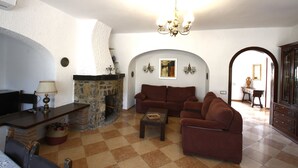 A living room with a fireplace, sofas, a coffee table, and a chandelier.
